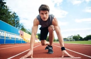 homme sportif de face mains au sol sur 1 piste au départ d''1 course de vitesse