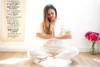 photo of a woman sitting on a rug in a room practising yoga