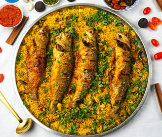 a pan of fish and rice with vegetables