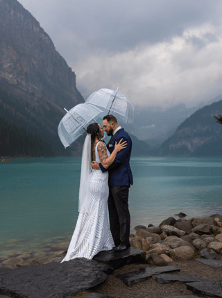 Couple eloping at Lake Louise holding clear umbrellas