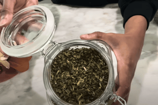 a person holding a jar of skullcap tea and a cup of tea