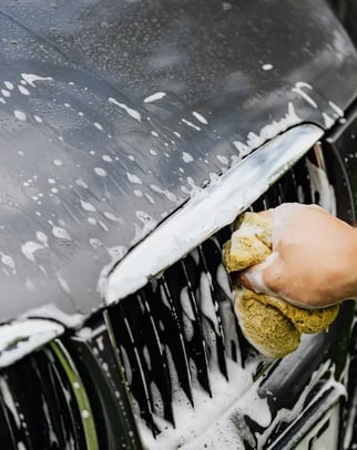 a person cleaning a car with a sponge pad