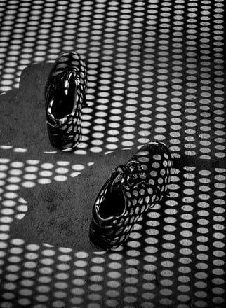 a pair of shoes on a surface with black and white shadows