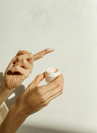 a woman holding a jar of cream open