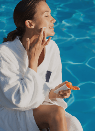 Girl applying SPF to her face as part of her Summer Skincare
