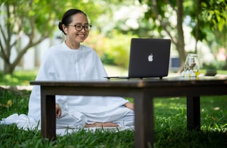 a woman sitting on a bench in a park giving online yoga sessions