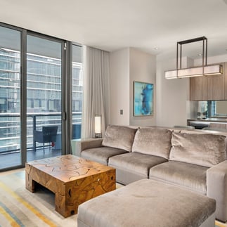 view of the living room of a room at the east hotel in miami with the city in the background through the windows