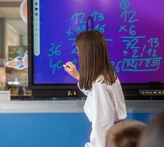Teacher using the TICTIC interactive whiteboard app to deliver visual lessons with touch-enabled tools in a smart classroom.