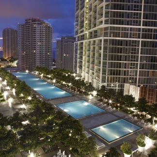 view of the pool of the Miami Vacation Rentals - Brickell hotel at night and you can see buildings in the background 