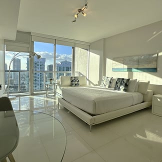 Miami Vacation Rentals room - White Brickell with the city in the background, through the window, a desk, a television