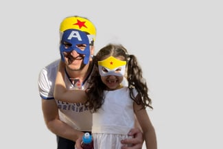un papa et sa fille posant avec des masques de super héros