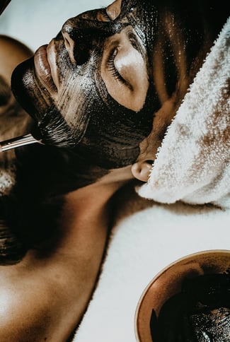 mulher deitada de olhos fechados fazendo argiloterapia.