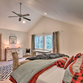 Large bedroom with mountain view window, desk, and cozy red-accented bed.