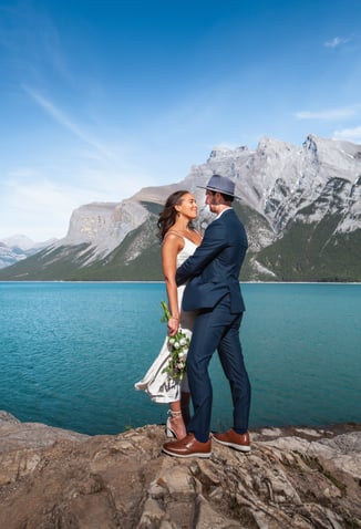 a bride and groom standing on a rock formation