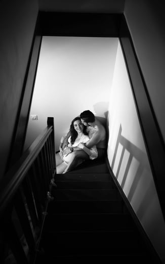 couple assis dans l'escalier pour une photo de grossesse