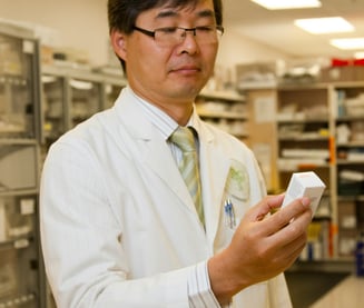 A pharmacist in a lab coat examining supplement ingredients for quality and safety