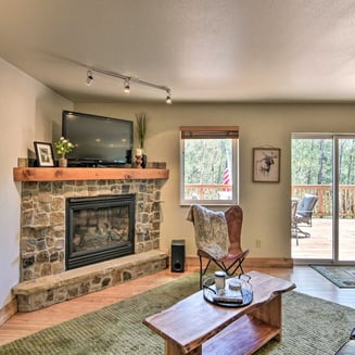 Stone fireplace and cozy lounge area with forest views and walk-out deck at Moose Creek Lodge.