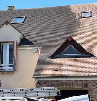 a truck with a ladder and a ladder in front of a house