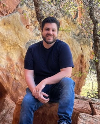 Christopher Carpenter sitting on a rock formation in the Utah mountains.