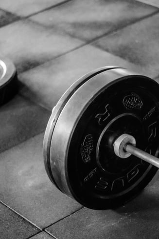 Greutăți contrastante, alb și negru, pe pardoseala sălii.