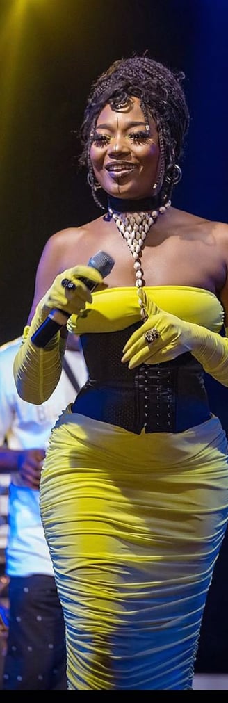 Efya Nocturnal looking stunning on stage in a bright yellow dress.