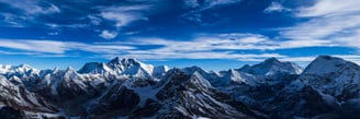 a mountain range with a blue sky and clouds