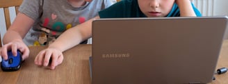 Two primary-age kids being creative with a laptop