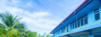 Blue grade school building with red roof and palm trees at Shelomith Learning Center, Inc.