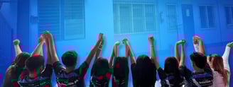 SLC students raising hands in triumph before school building, symbolizing unity, pride, and celebration.
