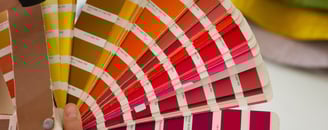 Mão segurando uma cartela com muitas cores possíveis para personalização da estampa das camisetas e