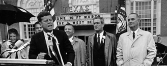 a man in a suit and tie standing in front of a crowd