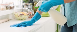 Agent de M & M Services Pro nettoyant une surface avec un spray nettoyant et des gants bleu à Rouen