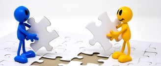 Two cartoon figures connecting puzzle pieces, symbolizing collaboration and integration
