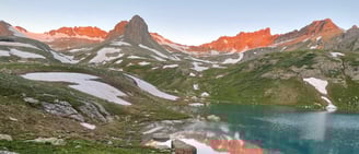 a beautiful mountain view near a lake with the sun rising outside