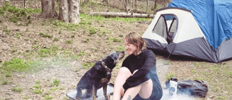Chels from the rewilding podcast and their dog carlo camping outside