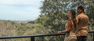 a man and woman standing on a balcony with a view of the ocean