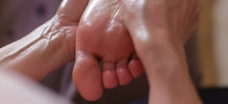 Mains massant un pied en douceur, symbole de soin ciblé et d’attention aux zones spécifiques.