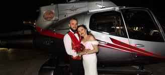 bride and groom taking photos by a helicopter