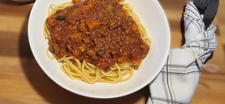 a bowl of spaghetti sauce with spaghetti and meat