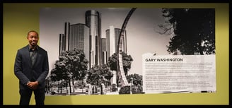 Photographer beside winning black and white photo at Detroit’s GMRENCEN exhibit.