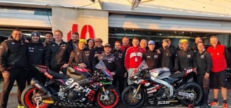 a motorcycle racing team standing around a motorcycle