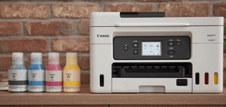 Canon MAXIFY GX4020 MegaTank Printer with four ink bottles on a wooden surface against a brick wall.