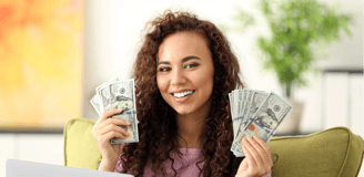 a woman sitting on a couch holding a laptop and holding money