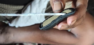 A Bastar artist carefully threading wax wires into a clay mould to craft intricate brass artwork using the lost-wax technique