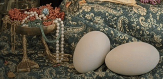 Bronze bowl with duck feet holding jewelry next to two duck eggs