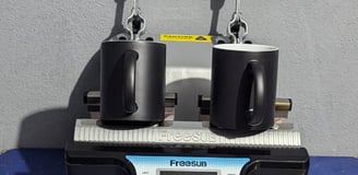 two black mugs siting on a mug press, with words below