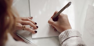 a woman is writing on a piece of paper