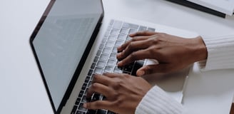 a person sitting at a table with a laptop and a glass of water