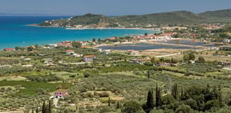 Vista da chegada à praia de Alykes, em Vólos, na Grécia, com o mar calmo ao fundo.