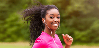 Une jeune femme noire aux cheveux naturels et un haut de sport rose qui fait son jogging